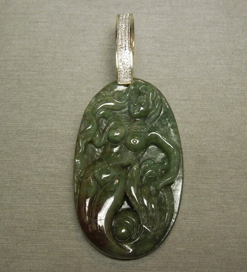May include: A green jade pendant featuring a carved mermaid with a diamond-encrusted bail.