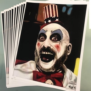 May include: A stack of art prints featuring a portrait of a clown with white face paint, red cheeks, and a red bow tie. The clown wears a top hat with red and white stripes and stars. The prints are signed "Milan '14".
