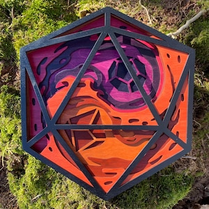 May include: A wooden, geometric, 3D wall art piece in the shape of a 20-sided die. The die is made of multiple layers of wood, with a swirling pattern of orange, red, and purple.
