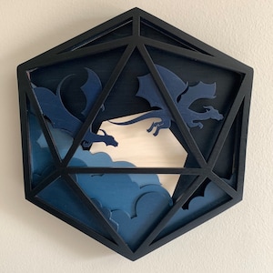 Op de afbeelding: Een zwarte houten 20-zijdige dobbelsteen met een blauw en wit ontwerp met twee draken die door wolken vliegen.