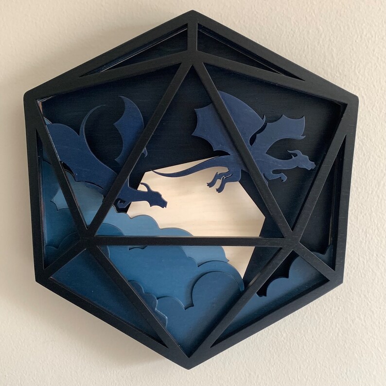 Op de afbeelding: Een zwarte houten 20-zijdige dobbelsteen met een blauw en wit ontwerp met twee draken die door wolken vliegen.