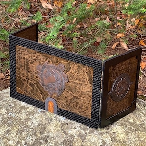May include: A three-panel wooden game board with a black and brown design. The center panel features a carved wooden dragon design and a small wooden door. The side panels have a black and brown design with a carved wooden dragon design.