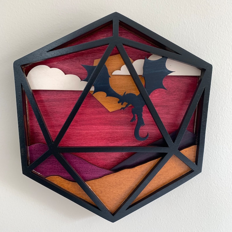 Op de afbeelding: Een houten, zwart geframed, geometrisch, veelkleurig, 3D wandkunstwerk dat een draak voorstelt die in een zonsonderganglucht vliegt.