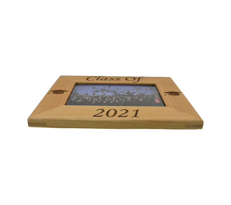Op de afbeelding: Een houten fotolijst met de tekst "Class of 2021" gegraveerd op de voorkant. De lijst heeft een afstudeerhoedje gegraveerd in elke hoek.