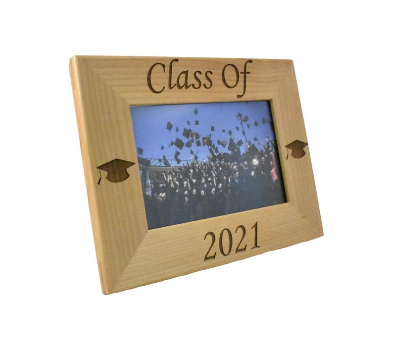 Op de afbeelding: Een houten fotolijst met de tekst "Class of 2021" gegraveerd aan de onderkant. De lijst heeft twee afstudeerhoeden in de bovenste hoeken gegraveerd.