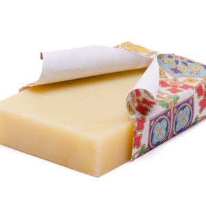 May include: A bar of natural soap wrapped in colourful patterned paper. The paper is partially peeled back to reveal the soap.
