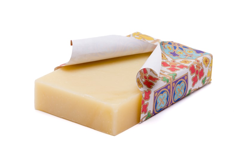May include: A bar of natural soap wrapped in colourful patterned paper. The paper is partially peeled back to reveal the soap.