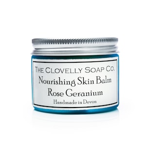 May include: A blue jar with a silver lid containing The Clovelly Soap Co. Nourishing Skin Balm Rose Geranium, handmade in Devon.