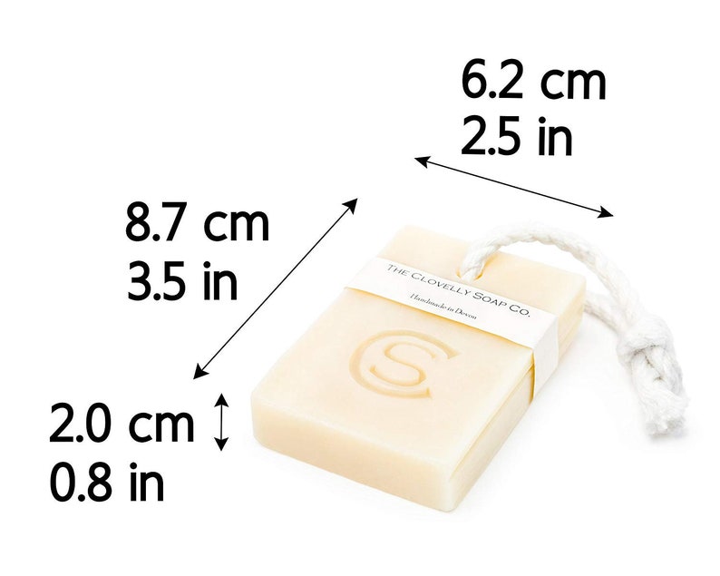 Puede incluir: Una barra de jab&oacute;n rectangular con una cuerda blanca atada. El jab&oacute;n est&aacute; etiquetado con "The Clovelly Soap Co. Handmade in Devon". El jab&oacute;n mide 8,7 cm de largo, 6,2 cm de ancho y 2 cm de grosor.