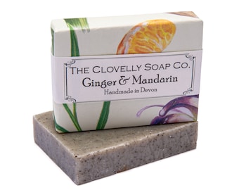 Puede incluir: Una pastilla de jabón artesanal en una caja blanca con un diseño floral. La caja tiene una etiqueta que dice "The Clovelly Soap Co. Ginger & Mandarin Handmade in Devon".
