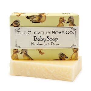 Può includere: Un sapone per bambini giallo con un'etichetta che recita "The Clovelly Soap Co. Baby Soap Handmade in Devon" e un motivo di anatroccoli gialli sul davanti e sul retro.