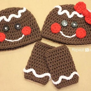 Pode incluir: Um conjunto de dois chapéus de crochê marrons em forma de homem de gengibre, com cobertura branca e detalhes de doces vermelhos. Um chapéu tem um laço de crochê vermelho. Os chapéus são emparelhados com luvas sem dedos de crochê marrons combinando com detalhes de cobertura branca.