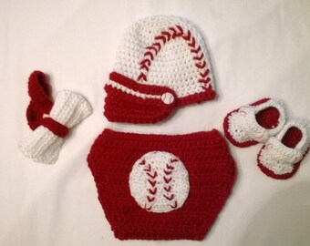 Può includere: Un completo per neonato all'uncinetto in rosso e bianco a tema baseball. Il completo comprende un cappello, un copri pannolino e scarpine.