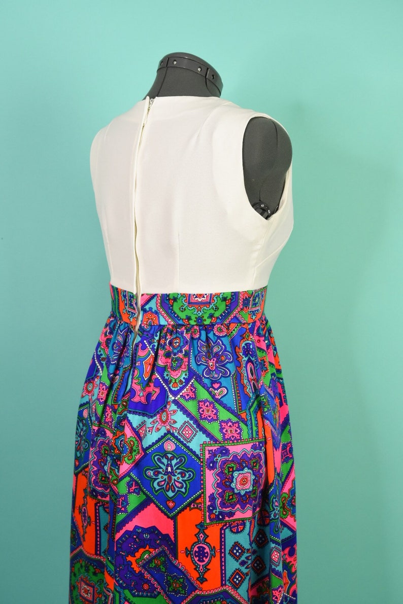 May include: A white sleeveless dress with a colorful geometric print skirt. The skirt features a variety of colors, including blue, green, pink, and orange.