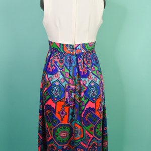 May include: A white sleeveless dress with a colorful geometric print skirt. The skirt features a mix of blue, green, pink, and orange colors.