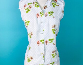 May include: A white sleeveless button-up shirt with a floral print and a white polka dot pattern.