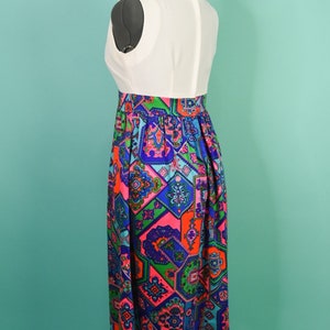 May include: A white sleeveless dress with a colorful geometric print skirt. The skirt is made of a patterned fabric with shades of blue, green, pink, and orange.