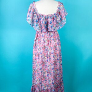 以下が含まれることがあります： ピンクとブルーの花柄のロングドレス。フリルネックと短い袖。ドレスは体にフィットしたボディとゆったりとしたスカートです。
