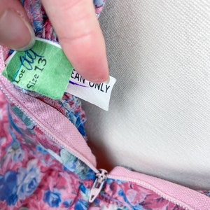 以下が含まれることがあります： ピンクとブルーの花柄のドレス。ピンクのジッパーと、緑色のタグには「Lot 40 Size 13」、白いタグには「Ean Only」と書いてあります。