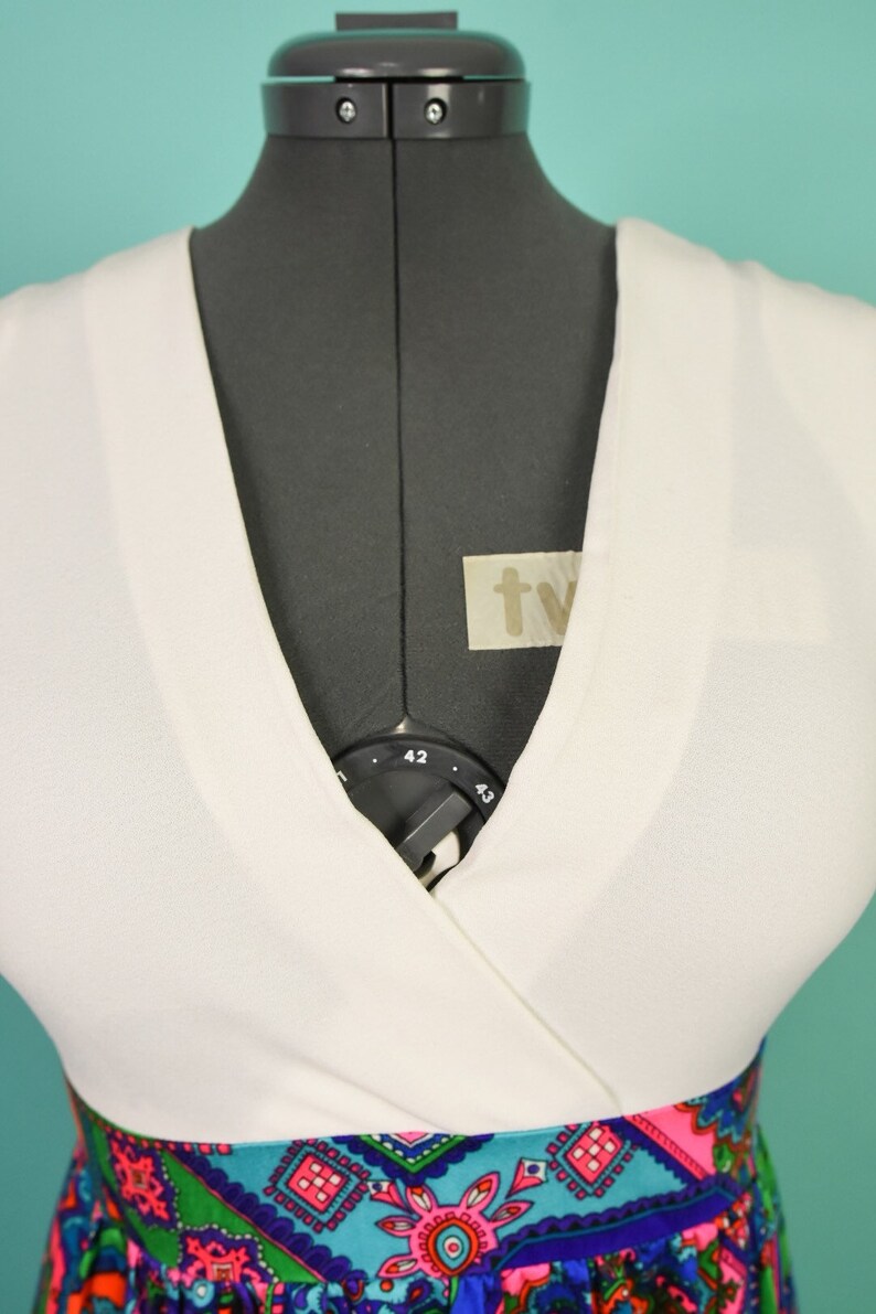 May include: White wrap dress with a colorful paisley print skirt. The dress has a V-neckline and a fitted bodice.