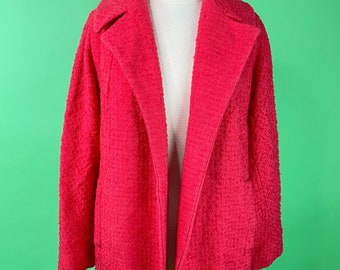 May include: A bright pink open-front jacket with a textured, fuzzy fabric. The jacket is on a white mannequin against a green background.