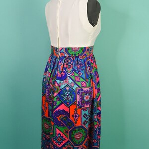 May include: A white sleeveless dress with a colorful geometric print skirt. The skirt features a variety of colors, including blue, green, pink, and orange.