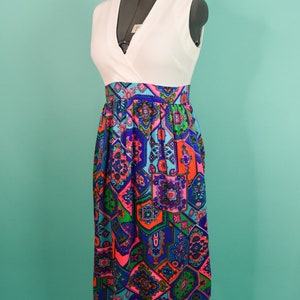 May include: A white sleeveless dress with a geometric print skirt. The skirt is a mix of blue, green, pink, and orange colors.