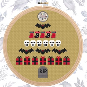 May include: A cross-stitch design in a wooden hoop features a Halloween-themed tree. The tree is composed of bats, stockings, skulls, gifts, and a tombstone with "RIP" on it. The design is stitched on a tan fabric.