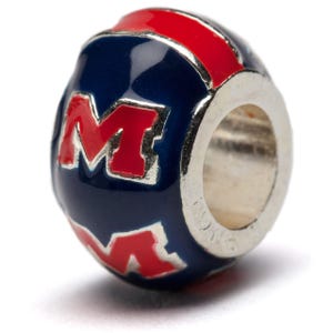 May include: A silver charm bead with a blue and red enamel design. The bead features the letter "M" in red with a white outline. The bead is designed for use with charm bracelets.