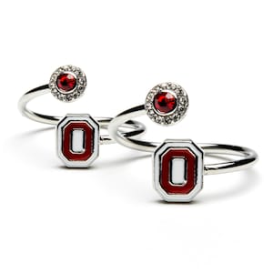 May include: Two silver rings with a red and white Ohio State University logo and a red rhinestone surrounded by clear rhinestones.