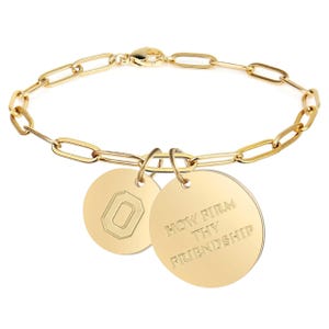 May include: A gold chain bracelet with two charms. One charm has the letter "O" engraved on it, and the other charm has the text "HOW FIRM THY FRIENDSHIP" engraved on it.