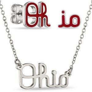 May include: A silver necklace with the name "Ohio" in a cursive font. Matching silver stud earrings and a pendant with the letters "OH" in red enamel are also shown. The jewelry set is displayed against a white background.