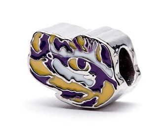 May include: A silver charm with a purple and gold LSU tiger head design.