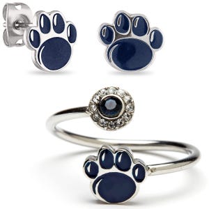 May include: A set of jewelry featuring a paw print design. The set includes a pair of silver stud earrings with blue enamel paw prints and a silver ring with a blue enamel paw print and a clear stone surrounded by smaller clear stones.