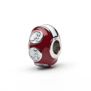 Puede incluir: Un charm redondo rojo y blanco con la letra "A" en blanco sobre un fondo rojo. El charm es una cuenta redonda con un agujero en el lateral para sujetarlo a una pulsera.