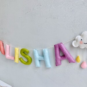 name banner in pastel rainbow shades with cute clouds.