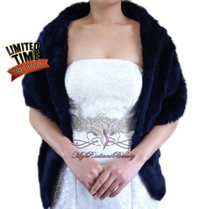 May include: A navy blue faux fur shawl with a satin trim. The shawl is draped over the shoulders of a person wearing a white strapless dress with a rhinestone belt. The text "My Radiant Beauty" is visible on the dress.