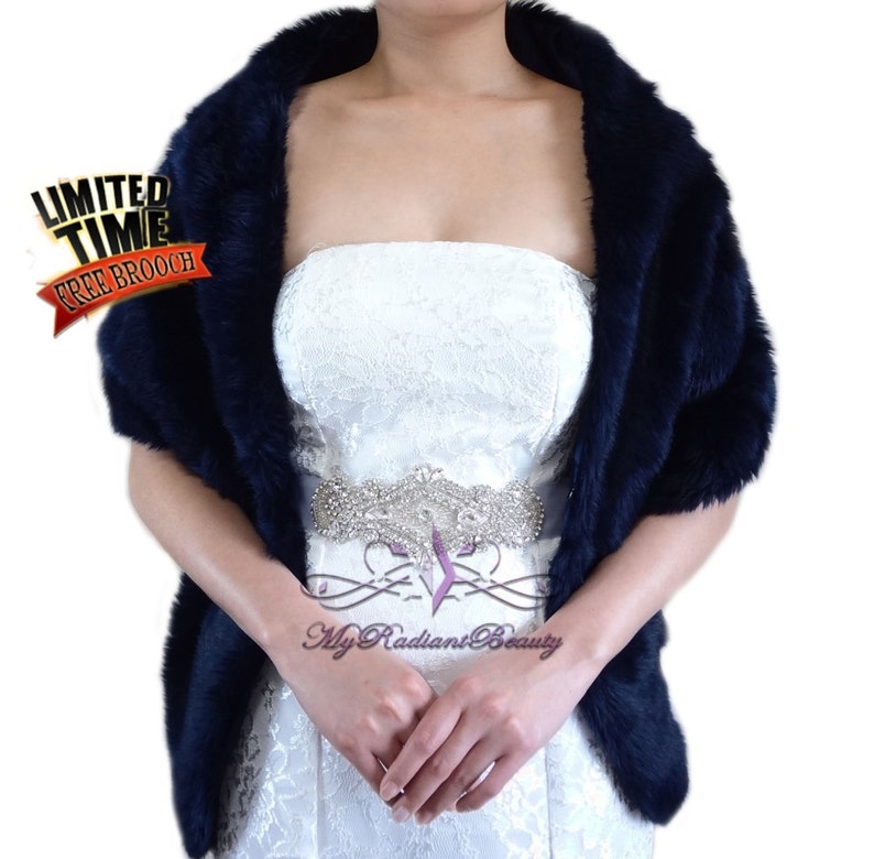 May include: A navy blue faux fur shawl with a satin trim. The shawl is draped over the shoulders of a person wearing a white strapless dress with a rhinestone belt. The text "My Radiant Beauty" is visible on the dress.