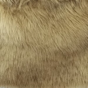 May include: Close-up of a soft, light brown faux fur fabric. The fur is long and fluffy, with a subtle sheen.