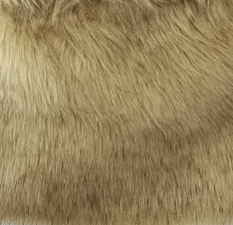 May include: Close-up of a soft, light brown faux fur fabric. The fur is long and fluffy, with a subtle sheen.