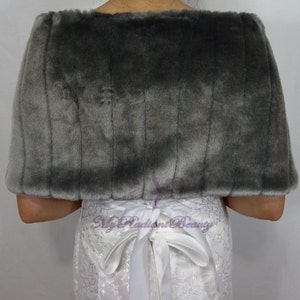 May include: Gray faux fur shawl with a white satin ribbon tied at the back. The shawl is soft and fluffy, and it would be a great addition to any winter wardrobe.