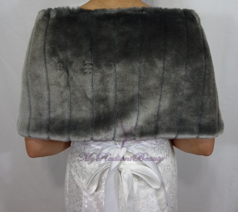 May include: Gray faux fur shawl with a white satin ribbon tied at the back. The shawl is soft and fluffy, and it would be a great addition to any winter wardrobe.