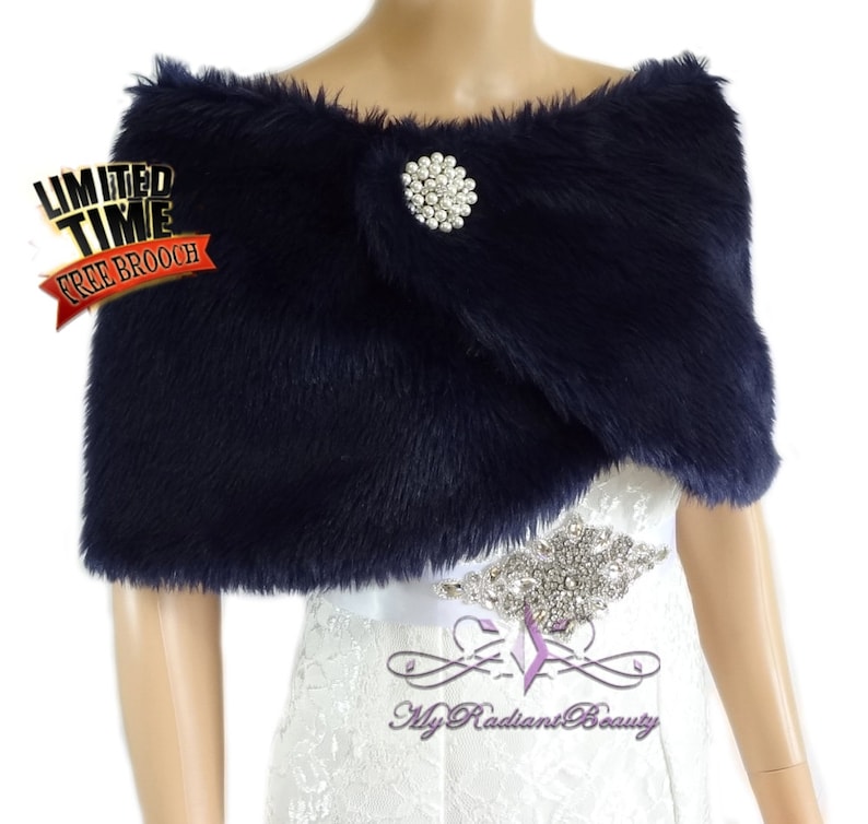 May include: A navy blue faux fur shawl with a rhinestone brooch. The shawl is draped over a white dress with a rhinestone belt. The text "Limited Time Free Brooch" is in the top left corner of the image.