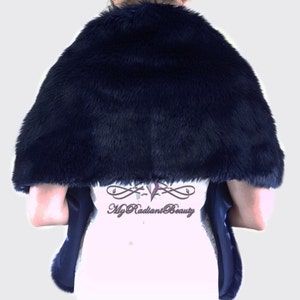 May include: A navy blue faux fur shawl with a satin lining. The shawl is draped over a person's shoulders and is shown from the back.