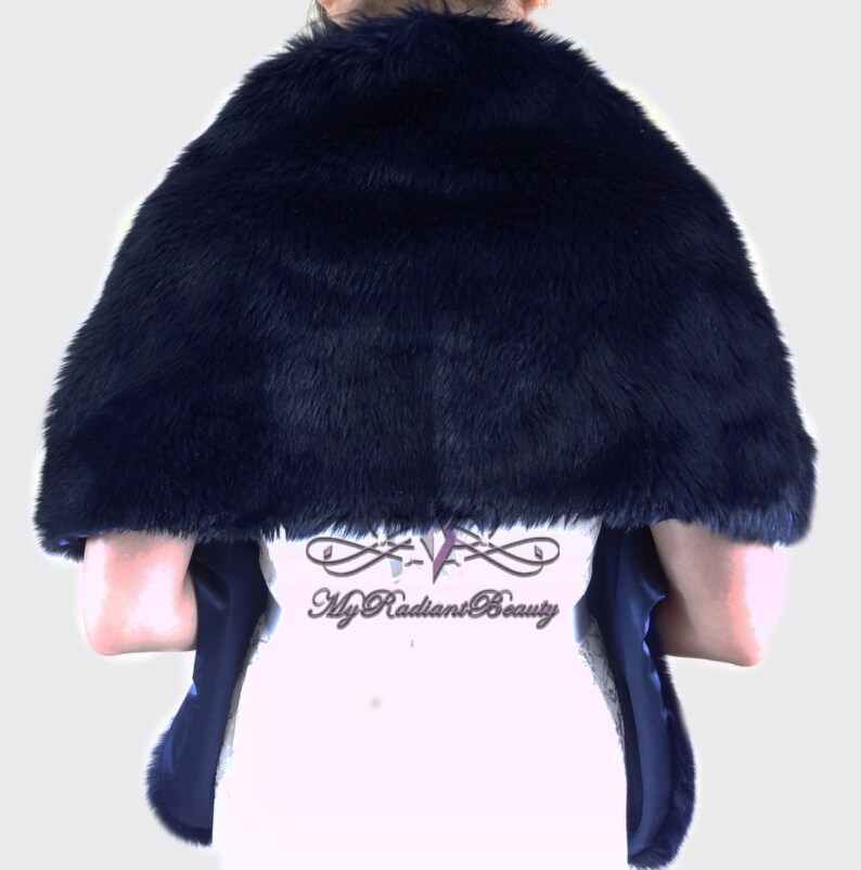 May include: A navy blue faux fur shawl with a satin lining. The shawl is draped over a person's shoulders and is shown from the back.