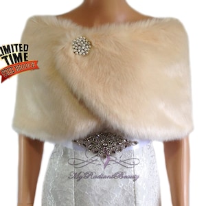 May include: A cream-colored faux fur shawl with a silver rhinestone brooch.  The shawl is draped over a white dress with a silver rhinestone belt.  Limited Time Free Brooch.