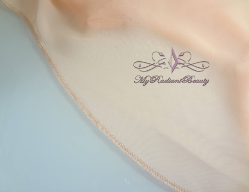 May include: Close-up of a peach-colored fabric with a stitched edge. The fabric has a subtle sheen and a soft, drapey texture. The text "My Radiant Beauty" is embroidered in a light purple color on the fabric.