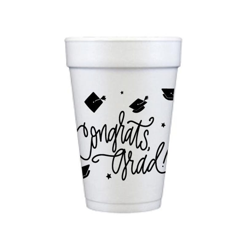 Puede incluir: Vaso de espuma blanco con gr&aacute;ficos de birretes negros y la frase "congrats, grad!" en cursiva. El vaso cil&iacute;ndrico con borde ligeramente ensanchado es ideal para celebraciones de graduaci&oacute;n.