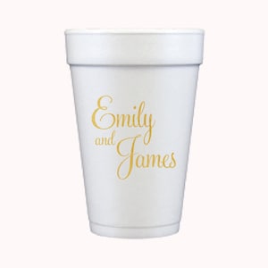 May include: A white foam cup with the names "Emily and James" in gold script. The cup has a slightly textured surface and a stepped rim. Ideal for a wedding or event.
