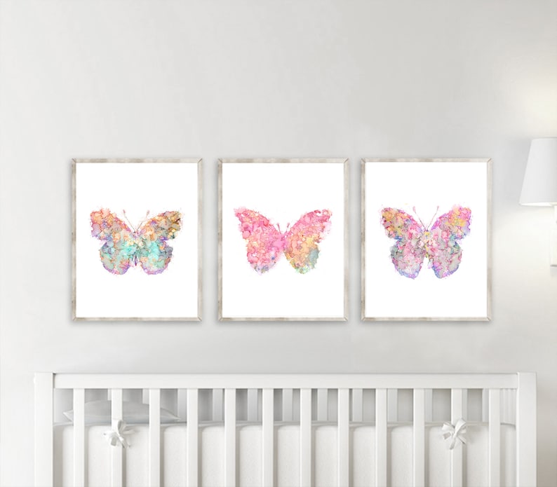 May include: Three framed prints of watercolor butterflies with pink, purple, and blue hues. The butterflies are set against a white background.